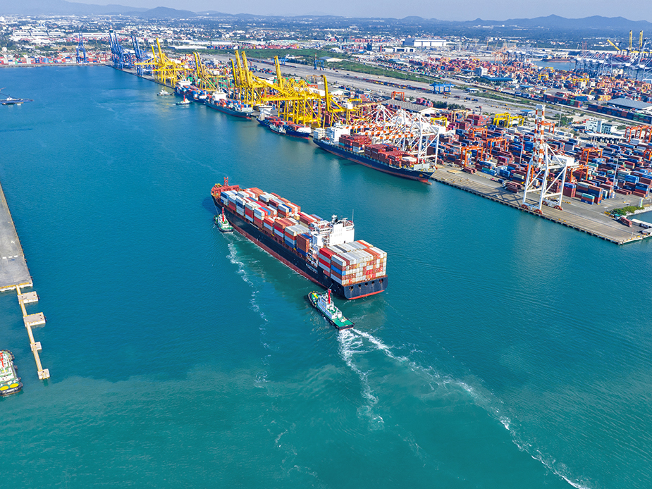 Seefracht Containerschiff, wie es mit zwei Schleppern in einen Hafen einläuft. Seefracht-Dienstleistungen